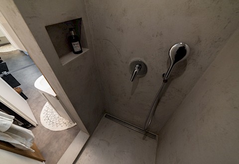 Sprchový kout má praktický betonepoxidový nátěr a nepravidelný půdorys přibližně 90x120 cm